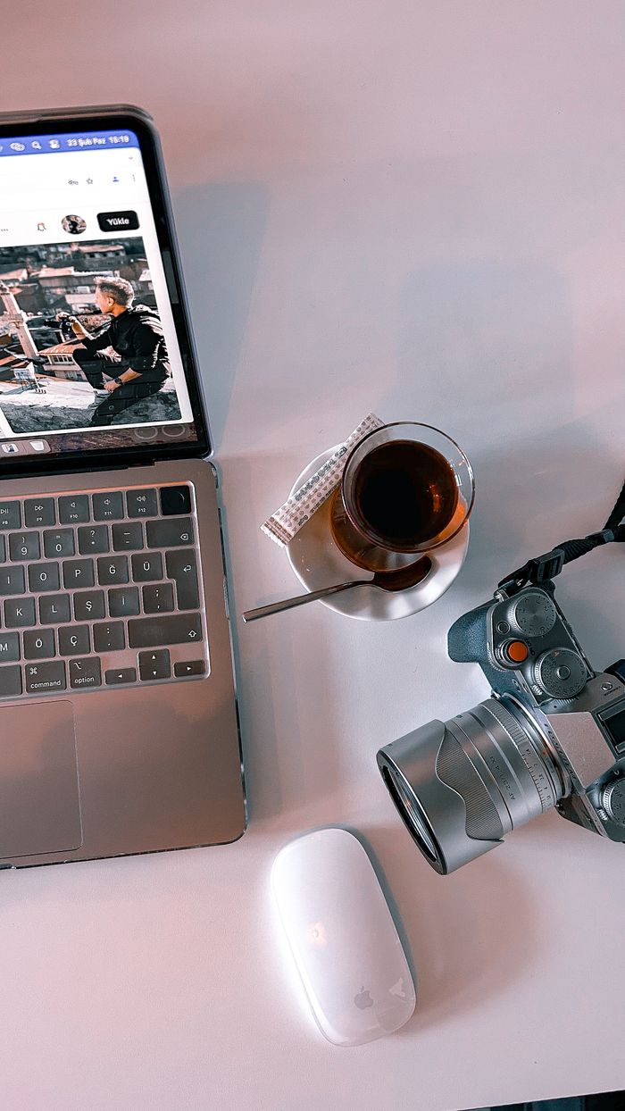 Contact Modern workspace with laptop, camera, and tea in an artistic flat lay.