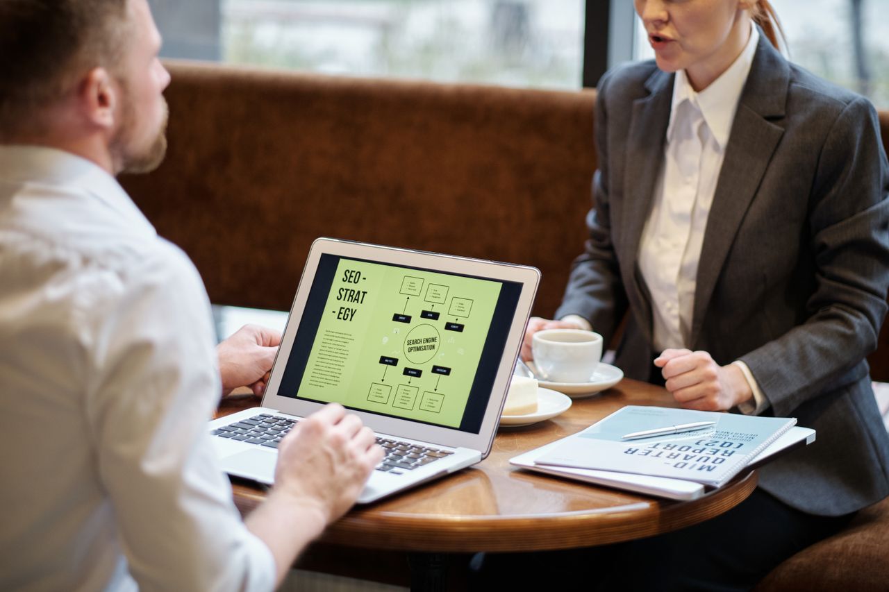 About A man and woman engaged in a business meeting discussing SEO strategy in a cozy cafe setting.